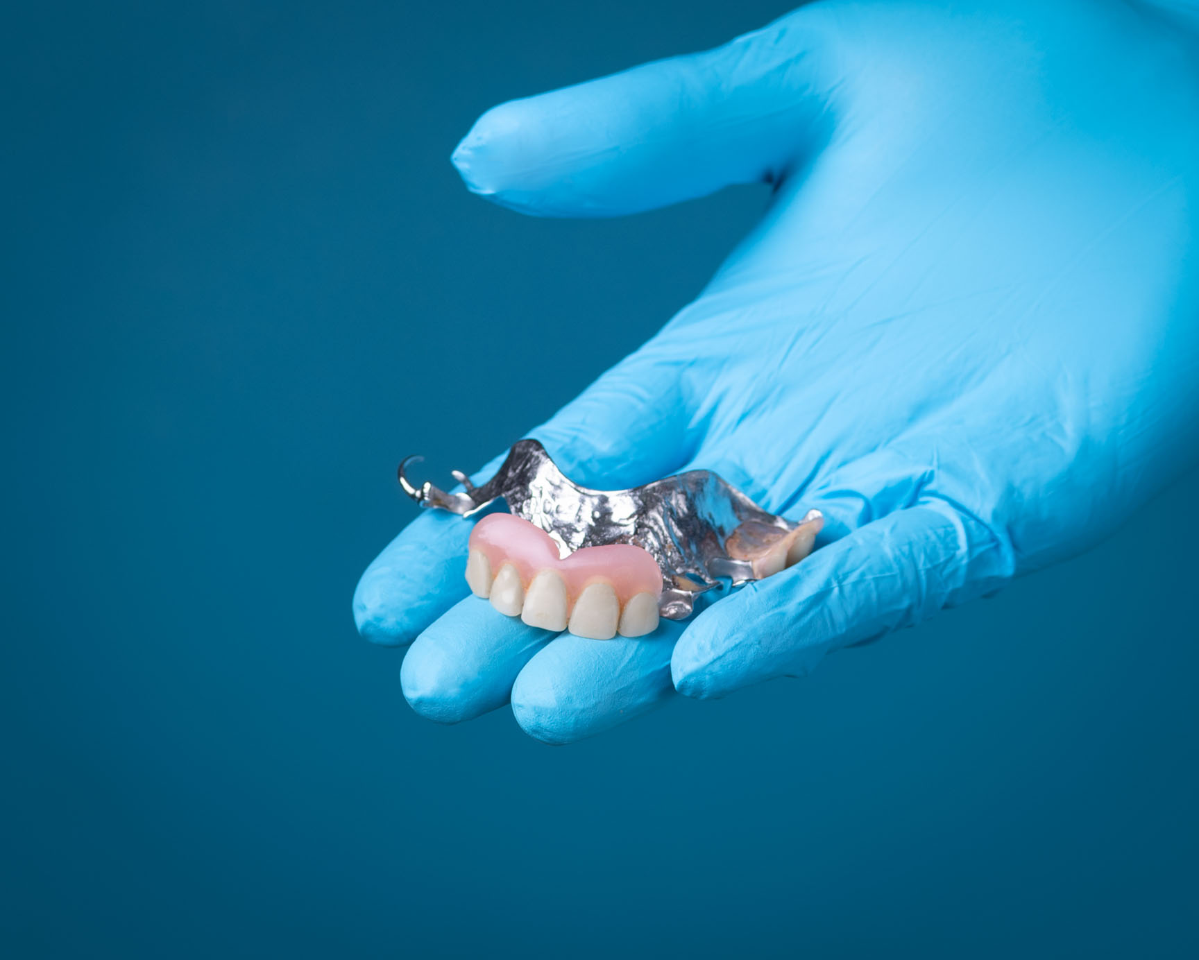 Partial denture held in gloved hand